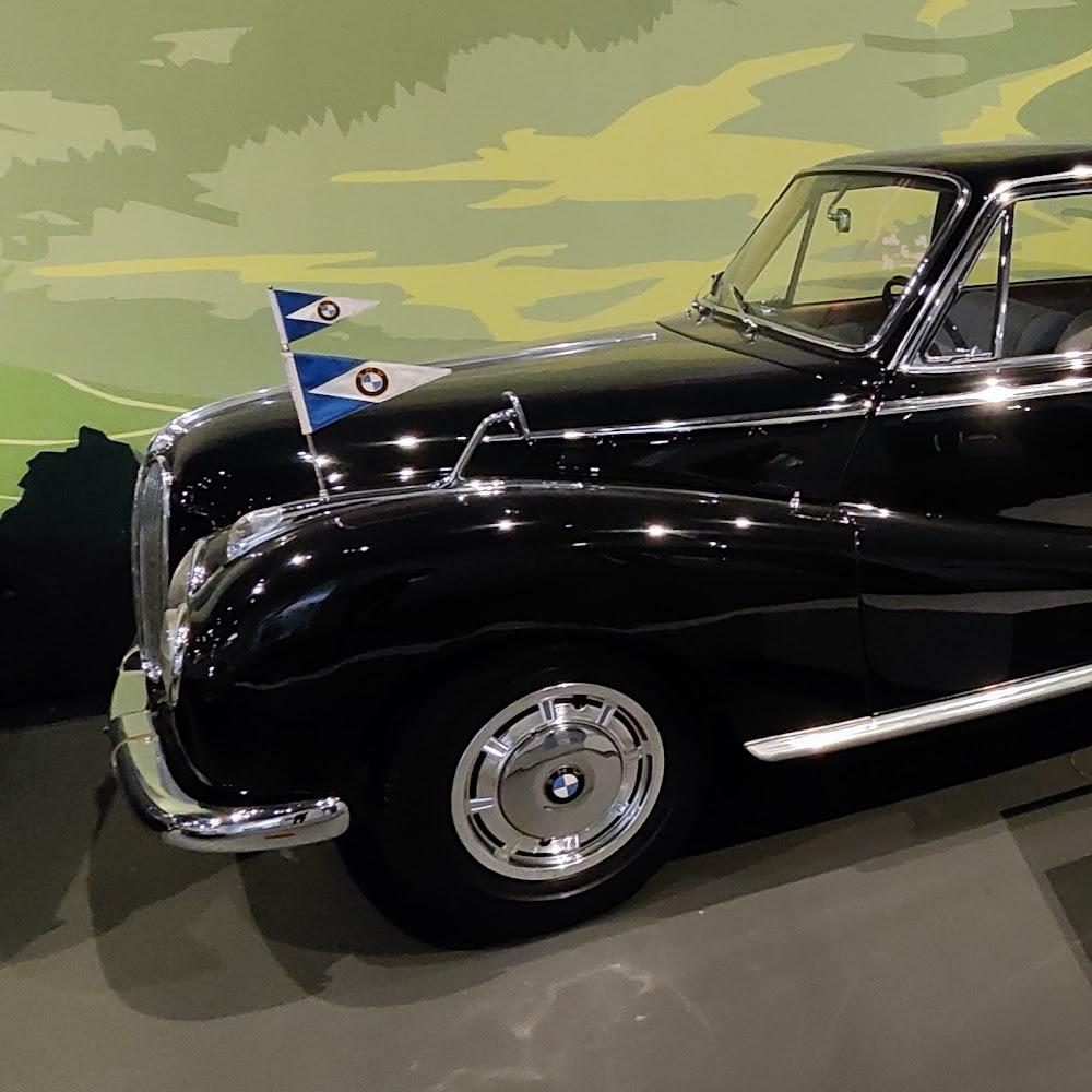Black classic car with BMW logo and flags.